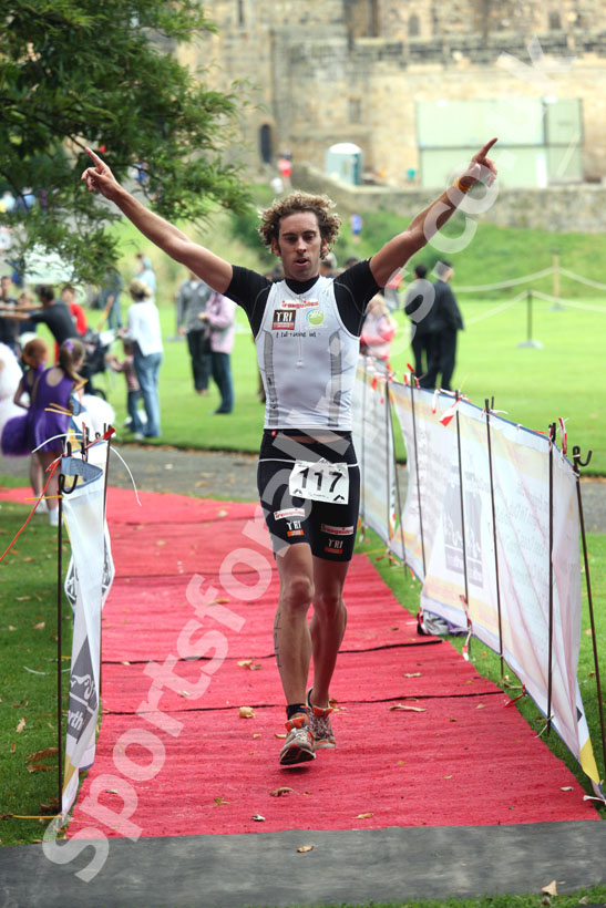 Alun Woodward from Hungary wins the Bamburgh Triathlon with Alnwick Castle as a backdrop